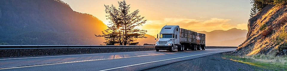 camion semi-remorque sur l’autoroute et soleil couchant en arrière-plan